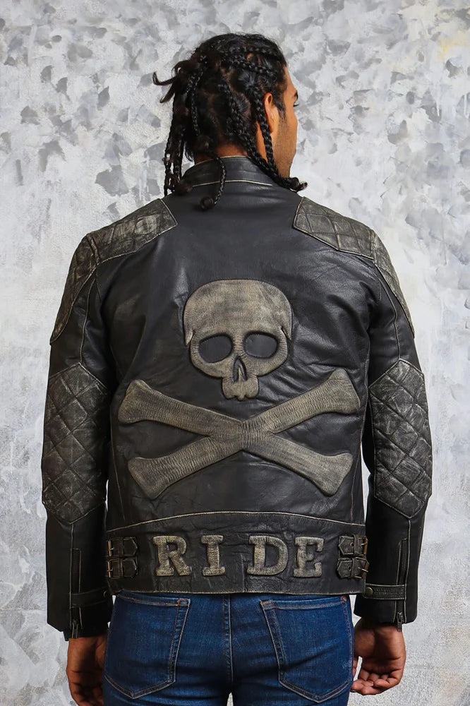 Person wearing a black leather jacket with skull and crossbones design on the back, against a textured gray background.